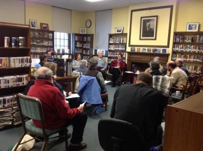 A group of seniors watching a speaker in a library