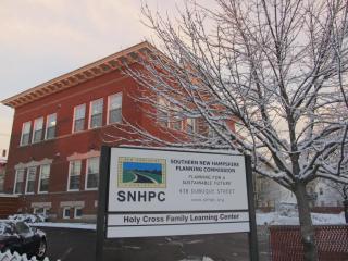 SNHPC offices in a brick building in the background with a white sign displaying the SNHPC logo and in the foreground