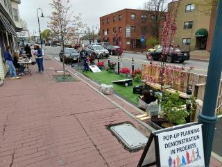 Photo of sidewalk with a park demonstration in the adjacent on-street parking space