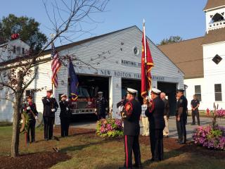 Photo of the New Boston Fire Department's Bunting Station with department staff conducting a ceremony in the foreground. 