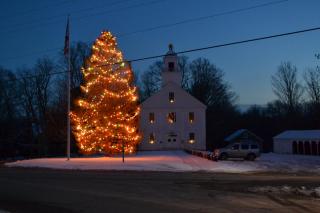 Historic Francestown building at twilight with a lit tree in the foreground